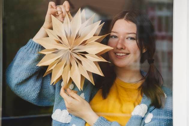 Smiling girl holding star shaped Christmas decoration seen through glass model released, Symbolfoto property released, IHF01786