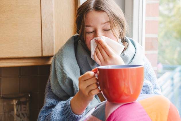 Teenage girl holding big coffee cup and cleaning nose with tissue at home model released, Symbolfoto property released, IHF01818