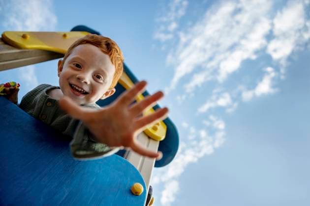 Creative Highlights Symbolbilder Smiling boy on playing equipment showing palm under sky model released, Symbolfoto, MBLF00085