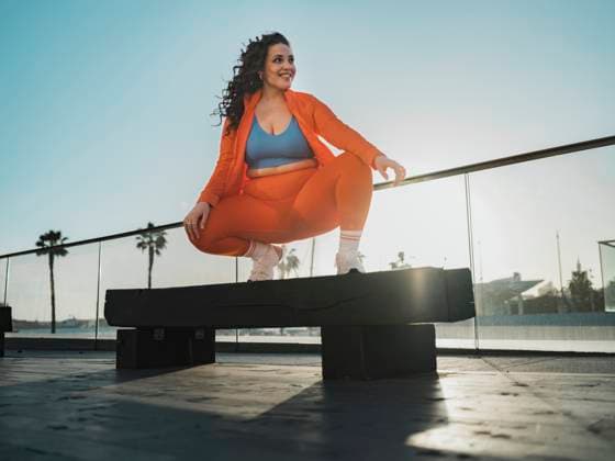 Creative Highlights Symbolbilder Smiling woman crouching on bench under blue sky model released, Symbolfoto, Spain MFF09405