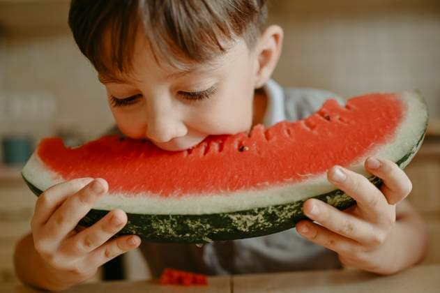 Creative Highlights Symbolbilder Boy eating slice of watermelon at home model released, Symbolfoto property released, ANAF02400