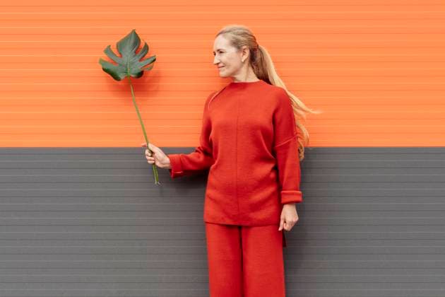 Creative Highlights Symbolbilder Blond woman with ponytail holding monstera leaf in front of wall model released, Symbolfoto, OSF02317