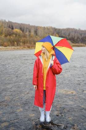 Contemplative woman wearing red raincoat standing with umbrella in river water model released, Symbolfoto, VBUF00493