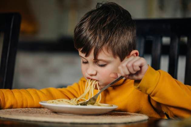 Hungry boy eating pasta at home model released, Symbolfoto, VSNF01415