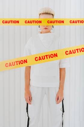 Creative Highlights Symbolbilder Young woman standing behind restriction tapes with eyes covered in front of wall model released, Symbolfoto property released, YTF01340