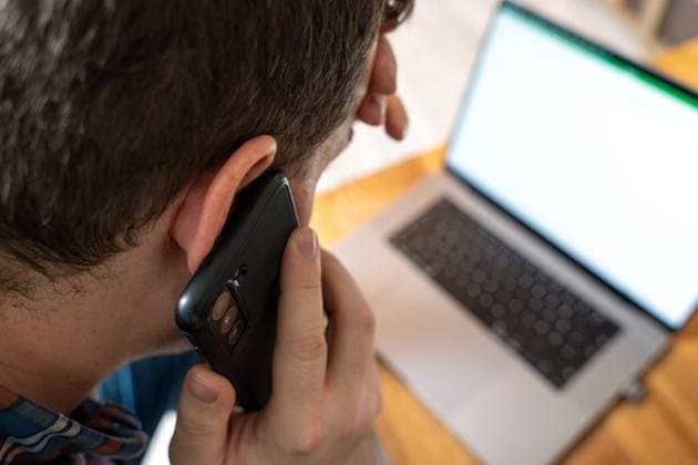 Bavaria, Germany - November 24, 2023: Man at work in the office. Phone calls with the smartphone, stress and burnout concept *** Mann bei der Arbeit im Büro. Telefonieren mit dem Smartphone, Stress und Burnout Konzept