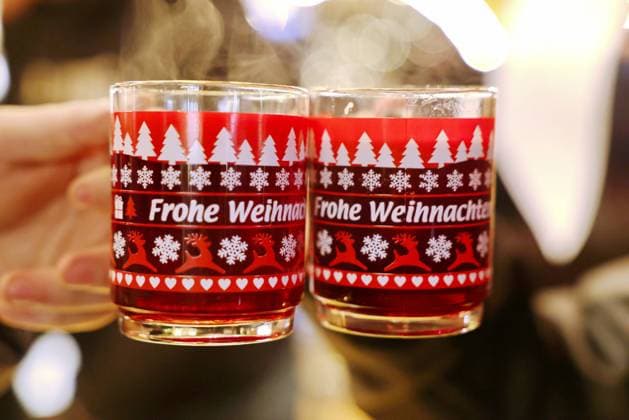 Feature Glühwein Hier: Zwei 2 Tassen Glühwein mit der Aufschrift Frohe Weihnachten werden hochgehalten auf dem Weihnachtsmarkt in Bonn *** Feature Glühwein Here Two 2 cups of mulled wine with the inscription Merry Christmas are held up at the Christmas market in Bonn MR:N