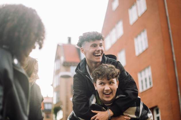 Creative Highlights Symbolbilder Low angle view of happy teenage boy piggybacking male friend in front of building Sweden, Stockholm, model released Copyright: xMaskotx , MA105375 MA105375