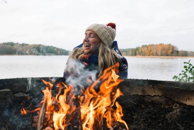 woman laughing wrapped in a blanket by a campfire Stockholm, Stockholm County, Sweden CR_RABE23112877-1287762-01 ,model released, Symbolfoto