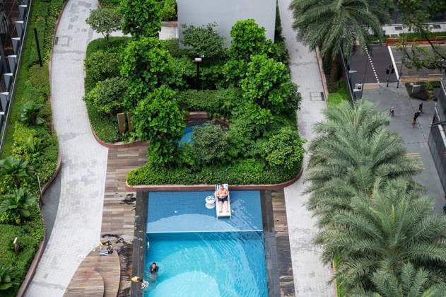 01.08.2023, Singapur, Republik Singapur, Asien - Blick von der Aussichtsterrasse Green Oasis des neuen CapitaSpring Wolkenkratzers auf die begruente Dachterrasse mit Swimming Pool der Citadines Appartements im Geschaeftszentrum am Raffles Place.