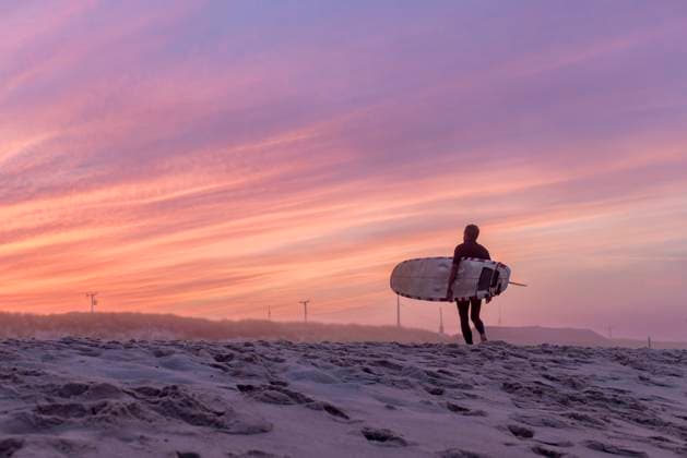 Creative Highlights Symbolbilder A surfer walks on the beach with his surfboard at sunset Orleans, Massachusetts, United States CR_JUCU231129F1-1272599-01 ,model released, Symbolfoto