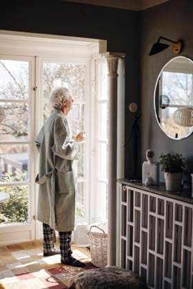 IMAGO Creative: Frühjahrsputz Senior man in bathrobe holding coffee cup while looking outside window at home Sweden, Gothenburg, model released, property released Copyright: xMaskotx , MA104731 MA104731