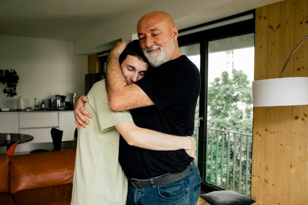 Side view of smiling man embracing son while standing at home Germany, Berlin, model released, property released Copyright: xMaskotx , MA105176 MA105176