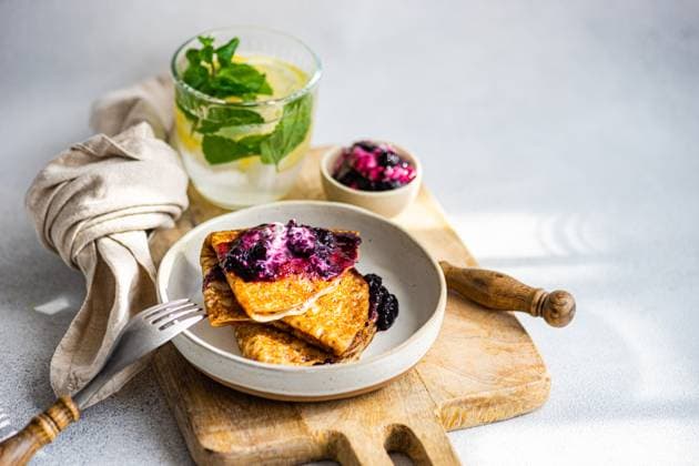 A stack of fresh, homemade crepes topped with blueberry jam and a dollop of sour cream, served with a refreshing mint-infused drink. Model Released AnnaBogush_ID17797_537128_005 Copyright: xAnnaxBogushx