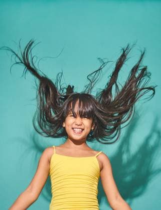 Creative Highlights Symbolbilder Smiling Asian girl with bare shoulders looking at the camera while standing with her hair flowing in the light against a turquoise background Model Released JoseDeJesusSaldana_ID16142_491277_002 Copyright: xJosexDexJesusxSaldanax RECORD DATE NOT STATED