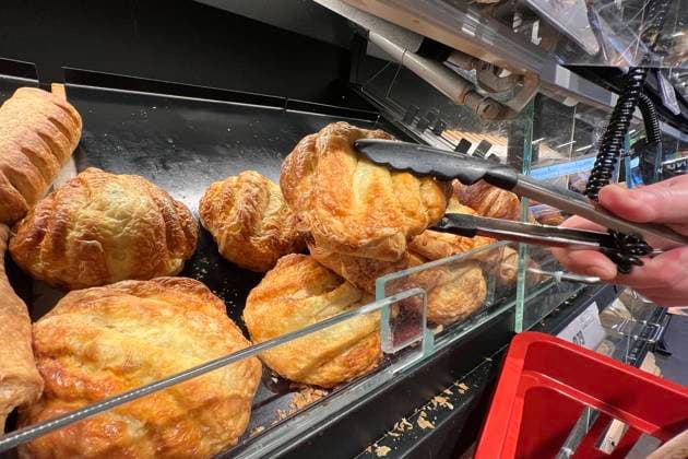Backwaren aus der Backtheke im REWE Supermarkt. Mit einer Zange wird Gebaeck aus der Theke entnommen. *** Baked goods from the bakery counter in the REWE supermarket Baked goods are removed from the counter with tongs
