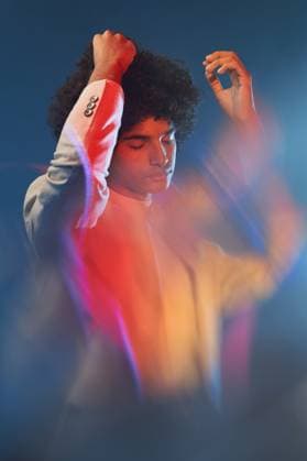 Creative Highlights Symbolbilder Young modern Hispanic guy touching Afro hair Young ethnic man with Afro hair and closed eyes wearing jacket raising arms against blue background with blur effect Model Released ManuelRuiz_ID13346_406939_005 Copyright: xManuelxRuizx RECORD DATE NOT STATED
