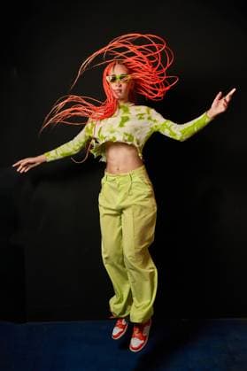 Creative Highlights Symbolbilder Trendy woman jumping in dark studio Full length of young stylish female wearing bright green outfit and sunglasses with colorful Afro braids jumping above ground against black background Model Released ManuelRuiz_ID16012_487647_017 Copyright: xManuelxRuizx