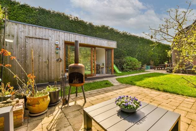 Backyard of house with shrubs Greenery yard of house with wooden table surrounded by green trees and potted plants under blue sky in summer day Model Released ProCreators_Dorpsstraat15_00014 Copyright: xProxCreatorsx