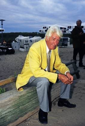 Rudi Carrell, niederländischer Showmaster, Sänger und Schauspieler, sitzt bei einer Stranparty auf einem Holzstamm, Deutschland um 1992. Copyright: HartwigxValdmanis Nur redaktionelle Nutzung. Editorial usage only. VAL_7205001524