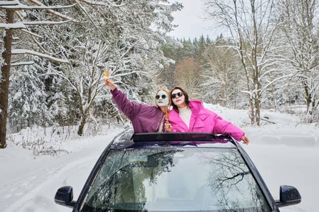 Creative Highlights Symbolbilder Zwei Frauen mit Gesichtsmasken, die ein Ereignis feiern und sich mit einem Glas Champagner aus der Autoluke lehnen *** Two Women with Face masks, the a Event celebrate and itself with a Glass Champagne from the Car hatch lean Copyright: imageBROKER/AlekseixIsachenko ibxaii09932898.jpg ,model released, Symbolfoto ,property released