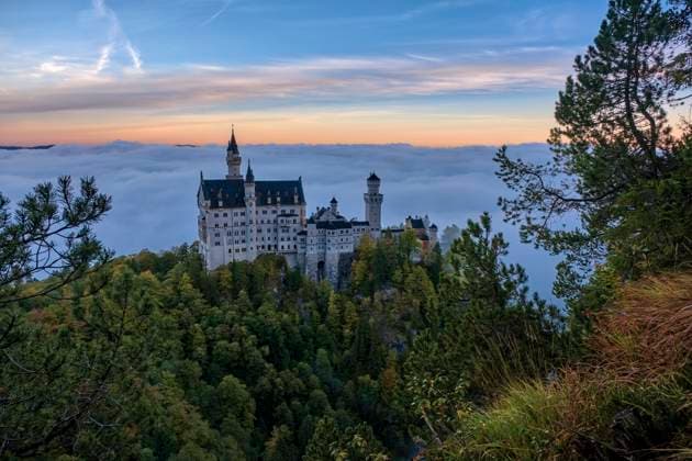 The castle Neuschwanstein, seen from the bridge Marienbrücke at sunrise in autumn, rising out of the fog. Hohenschwangau Bavaria Germany FB_2023_2870