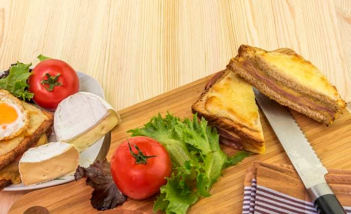 Sliced sandwich and fresh vegetables Delicious food on a wooden table, french sandwiches called croque madame and croque monsieur, tomatoes, white cheese and salad. Copyright: xZoonar.com DanielaxSimonaxTemneanux 9587075