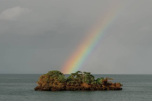 Creative Highlights World Vibrant rainbow over lush island in a calm ocean under cloudy skies. Samana, Samaná Province, Dominican Republic R_CUYS231208-1299619-01