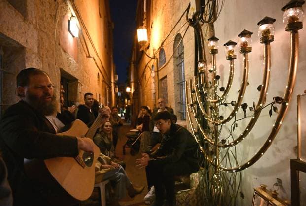 News Themen der Woche KW50 An Ultra-Orthodox rabbi plays the guitar in front of a large hanukkiyah, on the fifth night of the Jewish holiday of Hanukkah, the Festival of Lights, in Nachlaot in Jerusalem, on Monday, December 11, 2023. The eight day Hanukkah holiday commemorates the Maccabean victory over the Greek-Syrian Kingdom and the rededication of the Second Temple.  JER2023121116 DEBBIExHILL