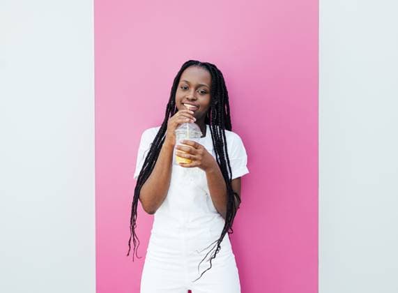 Creative Highlights Symbolbilder Young woman with braids holding a cocktail standing at a white wall with a pink stripe Young woman with braids holding a cocktail standing at a white wall with a pink stripe Copyright: xxx
