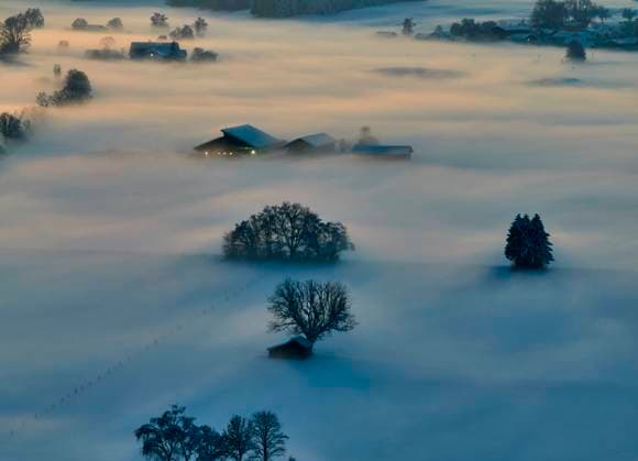 Drone photo of the Bavarian landscape with city view, fog in the evening short after sunset in Marktoberdorf, Germany, Dec 3, 2023.