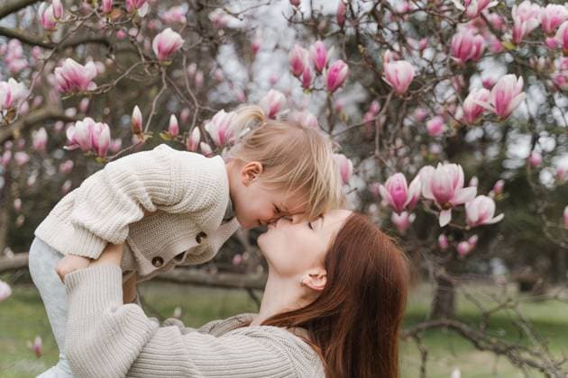 A woman kiss her little daughter near a blooming magnolia tree. Trezzo sull Adda, Lombardy, Italy CR_NEPM231207-1243991-01 ,model released, Symbolfoto