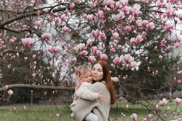 A woman hugs her little daughter near a blooming magnolia tree. Trezzo sull Adda, Lombardy, Italy CR_NEPM231207-1244000-01 ,model released, Symbolfoto