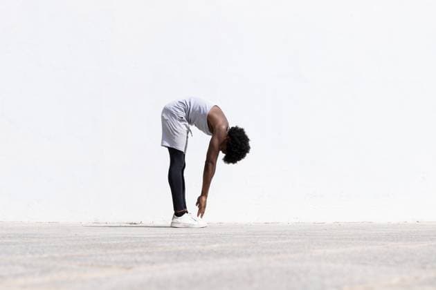 Creative Highlights Symbolbilder Full body side view of determined African American male athlete in sportswear bending forward and stretching arms on street against white wall Model Released MartinZubiriaPhotography_ID16842_514191_017 Copyright: xMartinxZubiriaxPhotographyx RECORD DATE NOT STATED