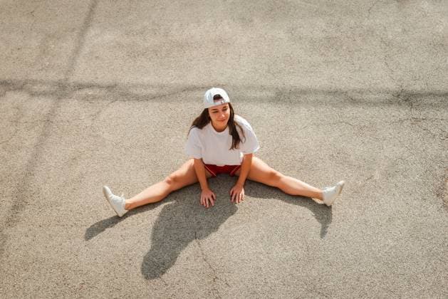 Creative Highlights Symbolbilder A young woman wearing a white cap and sports attire takes a break and sits on the concrete floor with her legs spread out Model Released NataliaPenado_ID18050_543068_003 Copyright: xNataliaxPenadox RECORD DATE NOT STATED