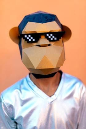 IMAGO Creative, Gesellschaft, Fasching Creative Highlights Symbolbilder Unrecognizable man in monkey mask standing against orange backdrop Anonymous male in silver V neck shirt and monkey mask with pixel party sunglasses looking at camera while standing against orange background in light Model Released SergioVictorVega_ID17382_528473_020 Copyright: xSergioxVictorxVegax