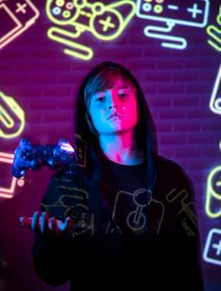 IMAGO Creative, Lifestyle, Gaming A young teen stands holding a game controller, bathed in the vibrant glow of neon lights with gaming symbols in the background. Model Released SergioVictorVega_ID17439_529355_007 Copyright: xSergioxVictorxVegax RECORD DATE NOT STATED