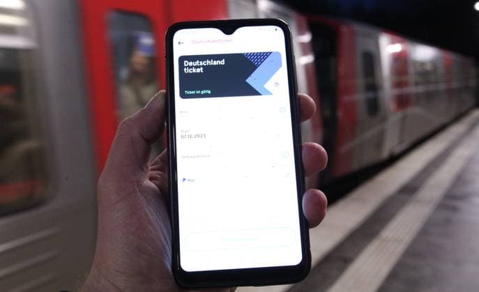 Ein Mann hält auf einem Bahnsteig sein Smartphone in der Hand, auf dem ein Deutschland-Ticket in der App des Hamburger Verkehrsverbundes ist. Symbolbild Symbolfoto Deutschlandticket. Eppendorf Hamburg