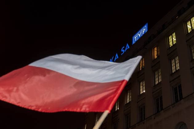 a waving Polish flag and the Polish Television (TVP) logo in the background during a demonstration in Warsaw in defense of Free Media . Warsaw 2023.12.14 Demonstration in defense of TVP. 2023 12 14 Copyright: xMarekxAntonixIwanczukx MAI06578