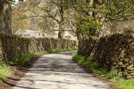 A walking trail surrounded by rocks and trees under the sunlight in the Peak District in the UK 186253 RECORD DATE NOT STATED