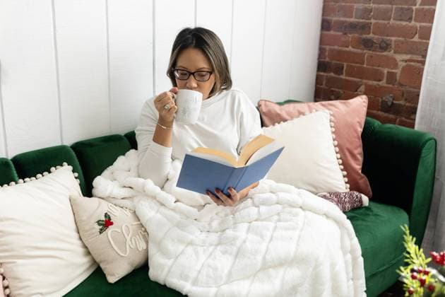 Woman sipping coffee and reading a book cozy on a couch United States, Connecticut, Plainville CR_ASOG231218-1304689-01 ,model released, Symbolfoto ,property released