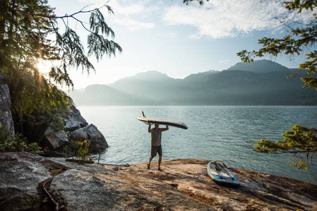 Man carries paddle board on head after an early morning paddle. Squamish, British Columbia, Canada CR_JDIP231218-1200114-01 ,model released, Symbolfoto