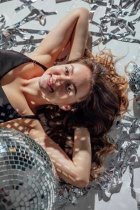 Creative Highlights Symbolbilder Smiling woman lying on ground near disco ball model released, Symbolfoto, ADF00263