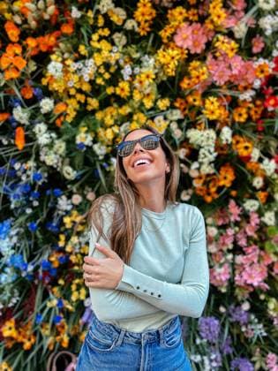 IMAGO Creative, Lifestyle, Frühling in der Stadt A woman in sunglasses with a cheerful expression, standing against a lively floral backdrop Model Released DavidPrado_ID18427_550249_073 Copyright: xDavidxPradox