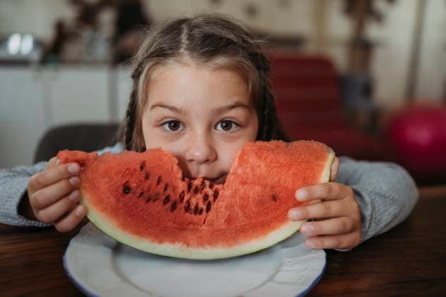 Creative Highlights Symbolbilder Girl eating slice of watermelon at home model released, Symbolfoto property released, ANAF02421