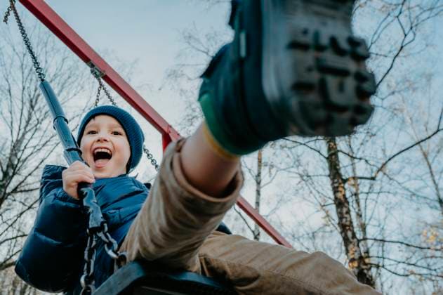 Creative Highlights Symbolbilder Cheerful boy playing on swing at park under sky model released, Symbolfoto, ANAF02460