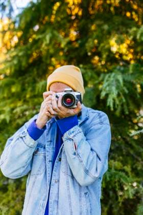 Man wearing knit hat and photographing through camera near tree model released, Symbolfoto, EGHF00805
