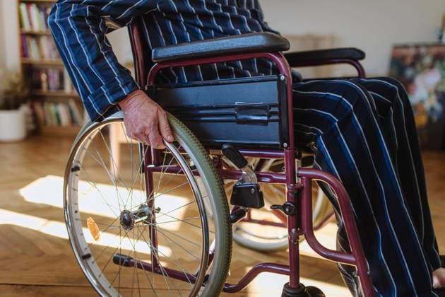 Senior man sitting and wheeling wheelchair at home model released, Symbolfoto property released, HAPF03348