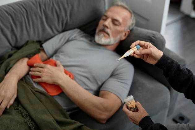 Unrecognizable woman looking at thermometer while sitting next to sick husband at home model released, Symbolfoto, KPEF00367