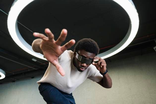 Creative Highlights Symbolbilder Young man with futuristic looking through cyber glasses under modern ring lamp reaching out hand model released, Symbolfoto, PNAF05293
